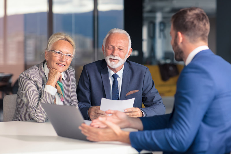 Mature man and woman sitting across the table from their insurance advisor